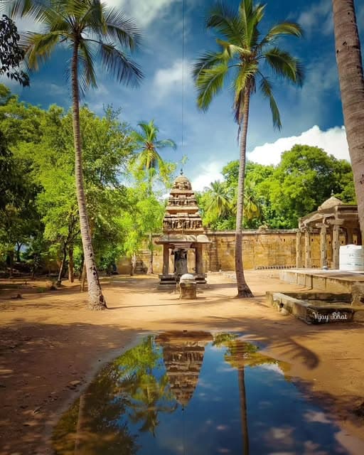 A peaceful heritage temple near Perambalur with stone carvings, tall palm trees, and calm natural scenery.