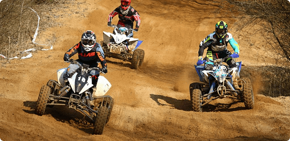 Riders speeding through a rugged dirt track on quad bikes during an exciting outdoor adventure race.