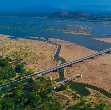 A wide river landscape with bridges, rocky banks, and distant hills creating a peaceful natural view.