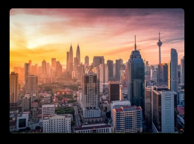 A vibrant city skyline at sunset featuring tall skyscrapers, glowing clouds, and a warm urban atmosphere