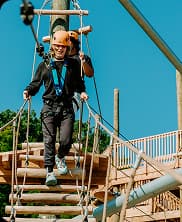 Participants enjoying outdoor adventure games on elevated platforms during team activities.