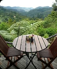 Outdoor café table overlooking a lush green valley offering a peaceful space for conversations.