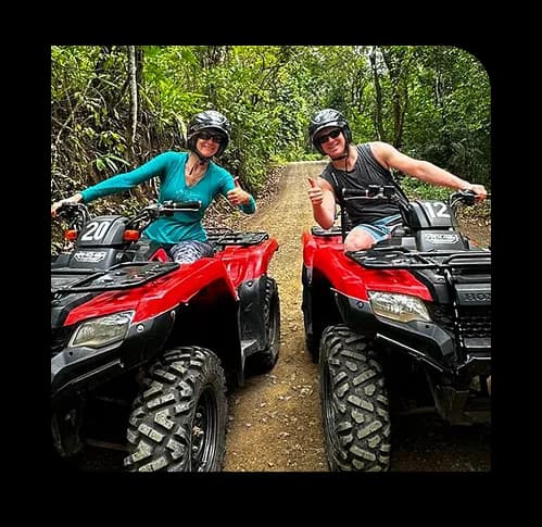 Two adventure seekers riding red ATVs through a forest trail at Adventures in Kolli Hills.