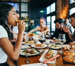 Travelers enjoying a shared dining experience with a table full of meals in a lively restaurant.