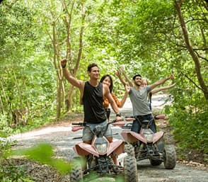 Group of adventure seekers riding ATVs through a lush forest trail enjoying an outdoor experience.