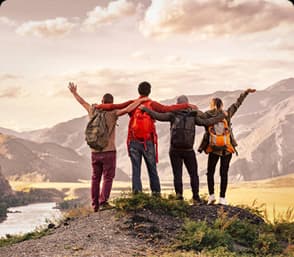 Group of hikers standing arm in arm enjoying a breathtaking mountain view under a warm sky.