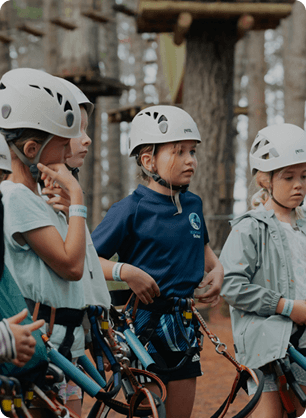 Young participants wearing helmets gather as certificates are handed out for completing outdoor activities.
