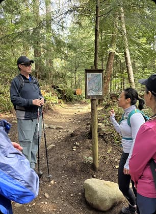 Group listening to a guide explain local ecology during an educational outdoor storytelling walk.