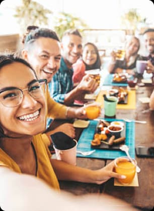 College friends take cheerful selfies and enjoy snacks together during a relaxed café networking session.
