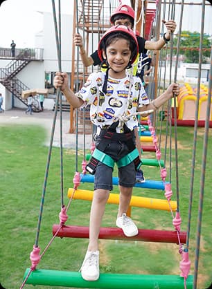 Children enjoying mini zip lines and rope climbing activities in a playful outdoor adventure zone.