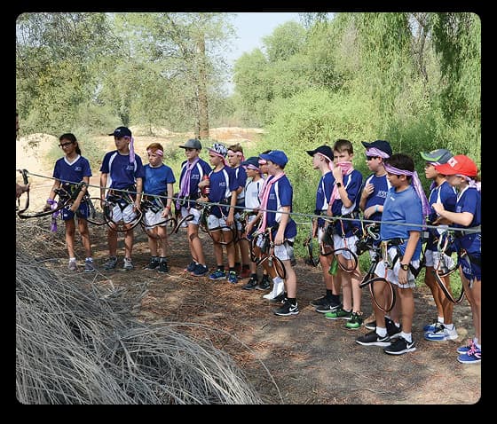 A group of students in safety gear stand together during an outdoor learning session on nature education