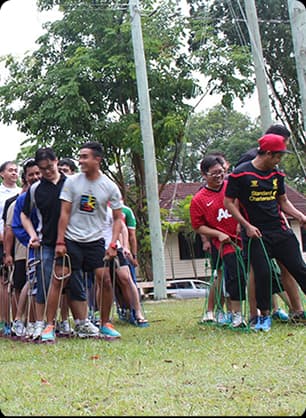 A group of college students participate in outdoor team games involving scoring, coordination, and roles.