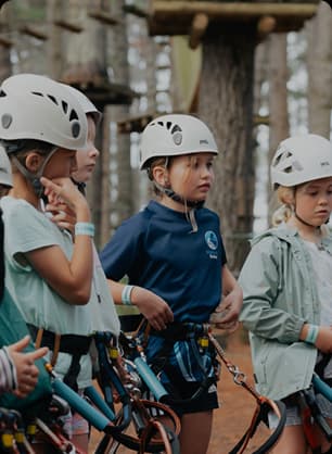 Young participants wearing helmets gather as certificates are handed out for completing outdoor activities.
