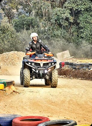 A college student rides a quad bike on a muddy adventure track during a thrilling outdoor activity event.