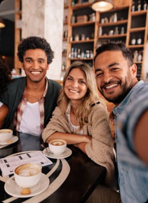 A group of smiling teens enjoy snacks together at a cozy café during the closing session of the day.