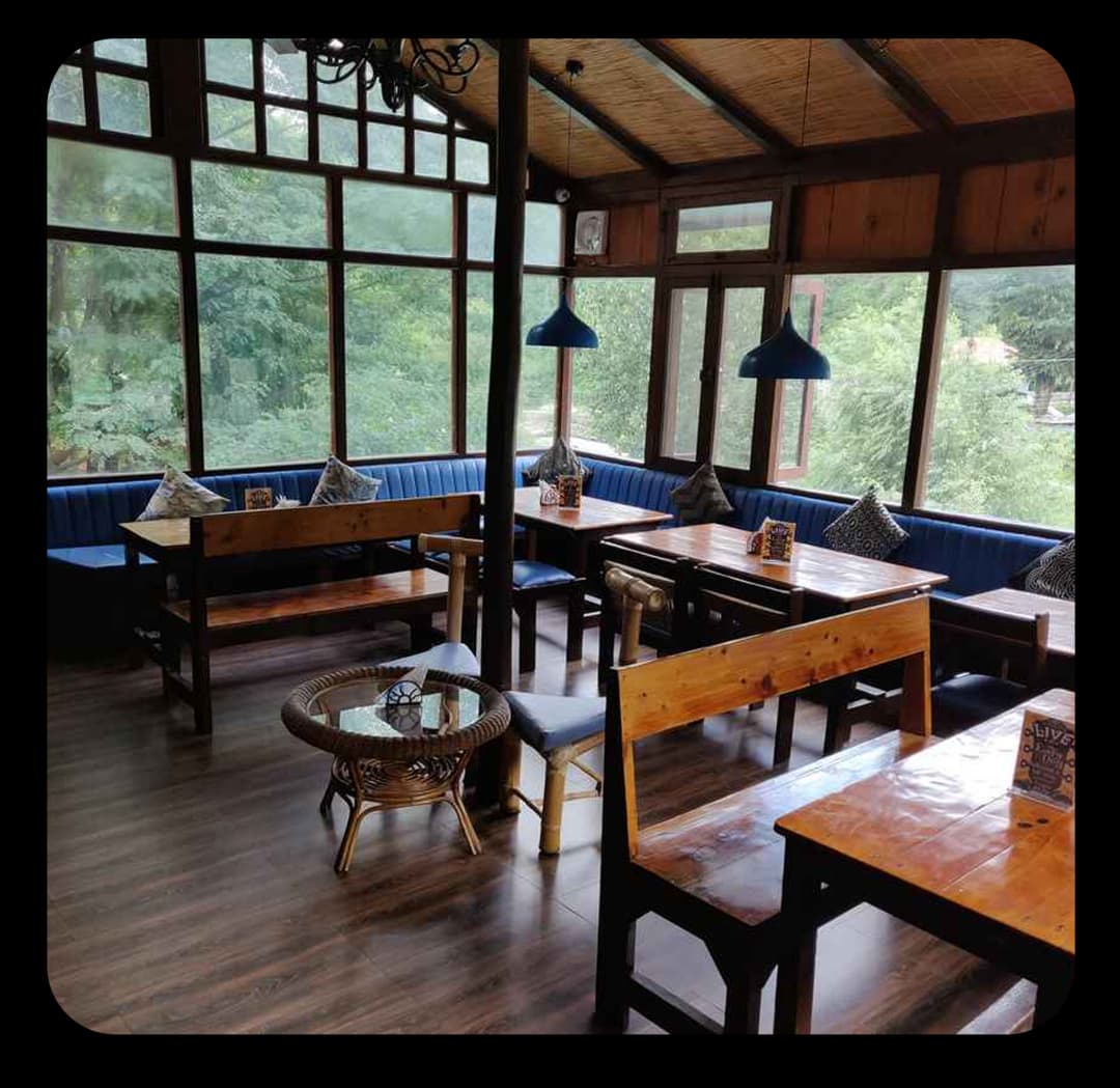 Dining Space with Scenic Views In Adventure Park Cozy wooden dining area with large glass windows comfortable seating and peaceful green views outside