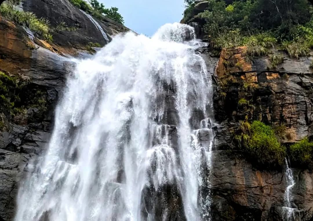 Beautiful Kolli Hills Waterfall Flowing over Rocky Cliffs Waterfall cascading down tall rocky cliffs surrounded by lush green vegetation in Kolli Hills