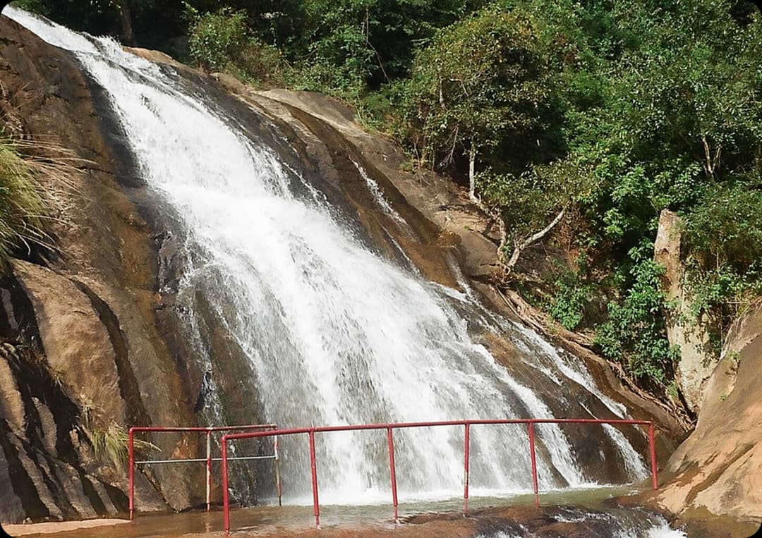 Peaceful Masila Falls Cascading Over Rocks in Kolli Hills Masila Falls gently flowing over smooth rocky slopes with green forest surroundings offering a calm natural spot